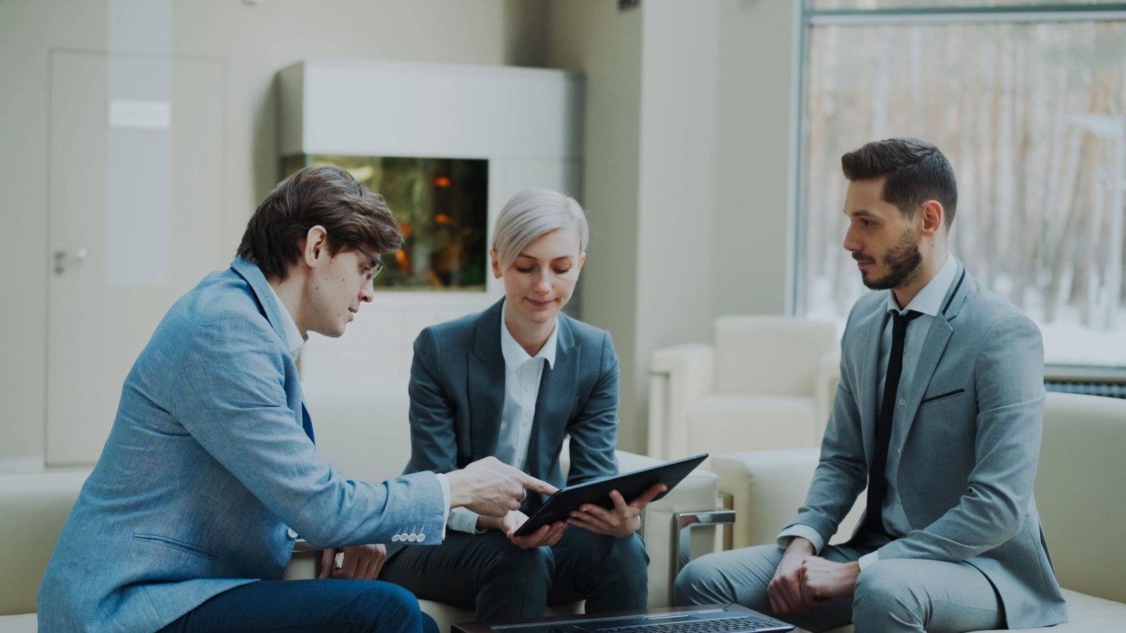 Three professionals engaging in a business meeting in a modern office setting.